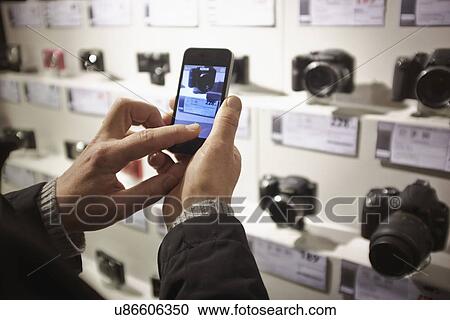 Mid adult man photographing camera's in shop display using smartphone View Large Photo Image Stock Image - Mid adult man photographing camera's in shop display using smartphone. Fotosearch