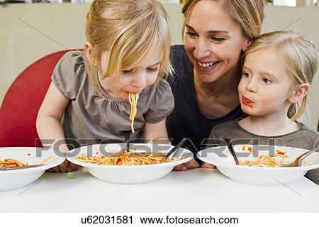Mid adult mother eating spaghetti with her two young daughters View Large Photo Image Stock Image - Mid adult mother eating spaghetti with her two young daughters. Fotosearch