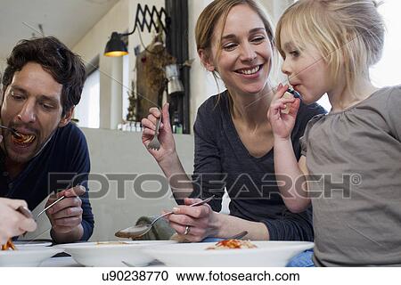 Mid adult parents and two daughters eating a spaghetti meal View Large Photo Image Stock Image - Mid adult parents and two daughters eating a spaghetti meal. Fotosearch