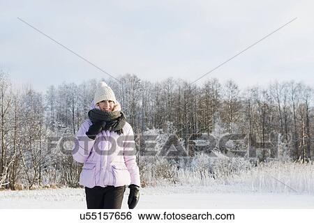 Stock Photograph - Mid adult woman wearing winter clothing in snow covered field. Fotosearch