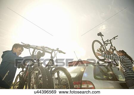 Stock Photo - Mother and son stacking bikes on bike rack. Fotosearch
