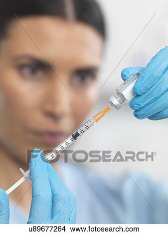 Nurse preparing a syringe for an injection View Large Photo Image Picture - Nurse preparing a syringe for an injection. Fotosearch