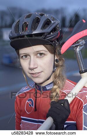 Stock Photo - Portrait of female cyclist with cycle on shoulder at velodrome. Fotosearch