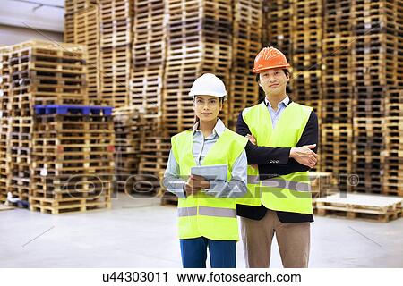 Stock Image - Portrait of male and female supervisors in distribution warehouse. Fotosearch
