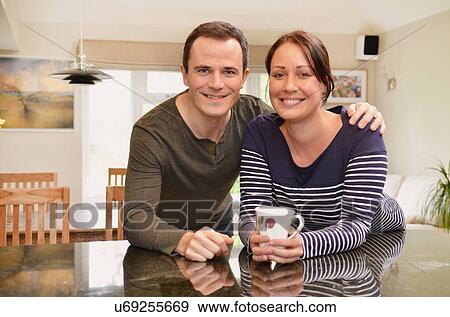 Portrait of mid adult couple leaning on kitchen counter View Large Photo Image Stock Photo - Portrait of mid adult couple leaning on kitchen counter. Fotosearch