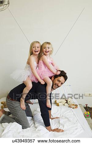 Portrait of mid adult father giving two young daughters a piggy back View Large Photo Image Stock Photo - Portrait of mid adult father giving two young daughters a piggy back. Fotosearch