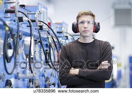 Stock Photograph - Portrait of mid adult male wearing ear protectors in engineering plant. Fotosearch