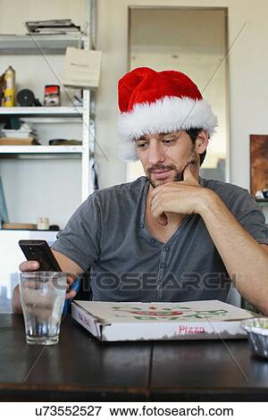 Portrait of mid adult man wearing santa hat looking at cellphone View Large Photo Image Stock Photo - Portrait of mid adult man wearing santa hat looking at cellphone. Fotosearch