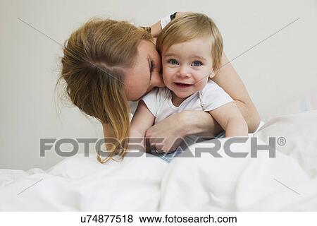 Portrait of mid adult woman hugging her year old baby girl View Large Photo Image Stock Photo - Portrait of mid adult woman hugging her year old baby girl. Fotosearch