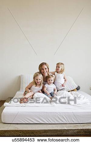 Portrait of mid adult woman in bed with three daughters View Large Photo Image Stock Image - Portrait of mid adult woman in bed with three daughters. Fotosearch