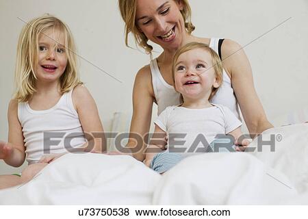 Portrait of mid adult woman in bed with two daughters View Large Photo Image Stock Photo - Portrait of mid adult woman in bed with two daughters. Fotosearch