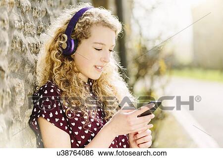 Portrait of teenage girl in village with headphones and smartphone View Large Photo Image Stock Photograph - Portrait of teenage girl in village with headphones and smartphone. Fotosearch