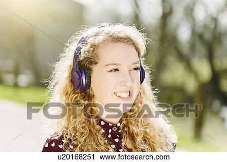 Stock Image - Portrait of teenage girl listening to headphones. Fotosearch