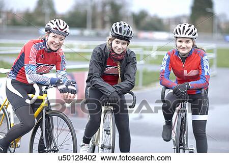 Stock Image - Portrait of three young female cyclists at velodrome. Fotosearch