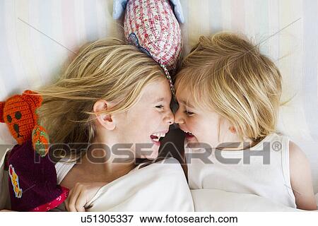 Portrait of two young sisters lying face to face in bed View Large Photo Image Stock Photo - Portrait of two young sisters lying face to face in bed. Fotosearch