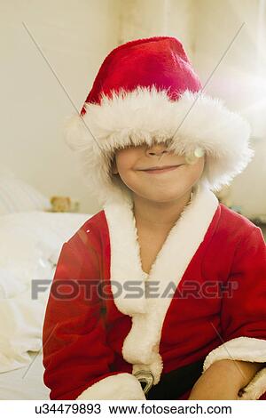 Stock Image - Portrait of young boy hidden by santa outfit cap. Fotosearch