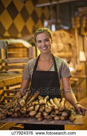 Portrait of young female baker carrying a tray of breadsticks View Large Photo Image Stock Photograph - Portrait of young female baker carrying a tray of breadsticks. Fotosearch