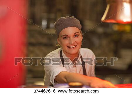 Portrait of young female chef serving over cafe counter View Large Photo Image Stock Photograph - Portrait of young female chef serving over cafe counter. Fotosearch