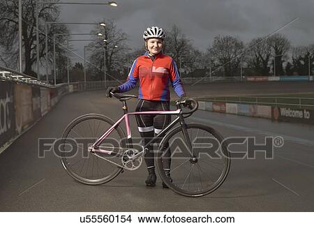 Portrait of young female cyclist with cycle at velodrome at night View Large Photo Image Picture - Portrait of young female cyclist with cycle at velodrome at night. Fotosearch