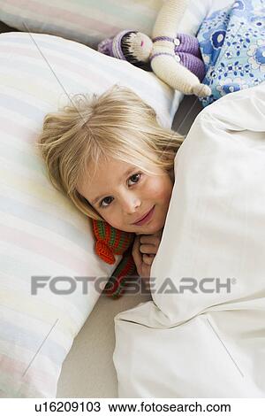 Portrait of young girl lying in bed with doll View Large Photo Image Stock Image - Portrait of young girl lying in bed with doll. Fotosearch