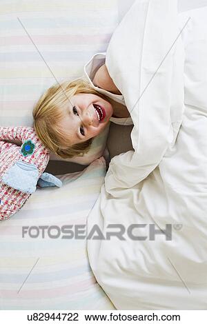 Portrait of young girl lying in bed with toy elephant View Large Photo Image Stock Image - Portrait of young girl lying in bed with toy elephant. Fotosearch