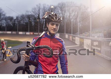 Portrait of young male cyclist carrying cycle at velodrome View Large Photo Image Stock Image - Portrait of young male cyclist carrying cycle at velodrome. Fotosearch
