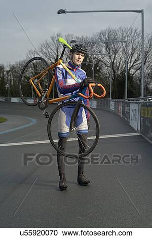 Stock Image - Portrait of young male cyclist carrying cycle at velodrome. Fotosearch