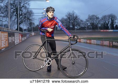 Portrait of young male cyclist with cycle at velodrome at night View Large Photo Image Stock Photo - Portrait of young male cyclist with cycle at velodrome at night. Fotosearch