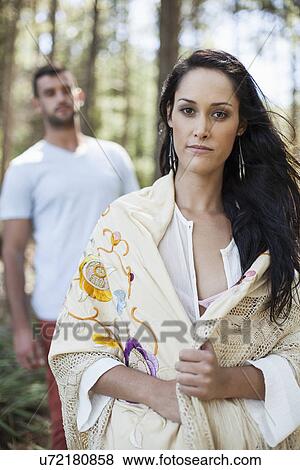 Portrait of young woman with young man behind her, in forest View Large Photo Image Stock Photo - Portrait of young woman with young man behind her, in forest. Fotosearch