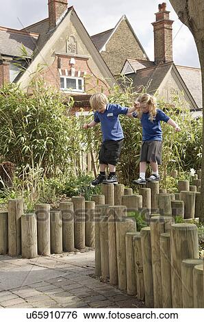 School boy and girl balancing on log fence View Large Photo Image Stock Photograph - School boy and girl balancing on log fence. Fotosearch