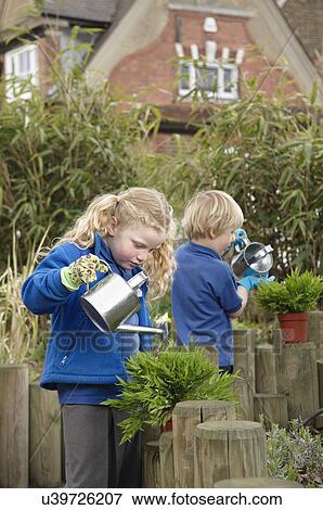 School boy and girl watering plants in garden View Large Photo Image Stock Photo - School boy and girl watering plants in garden. Fotosearch