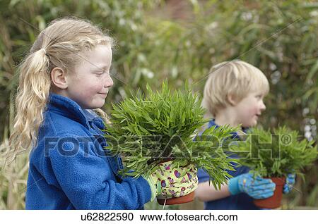 Stock Image - School boy and girl with plants in garden. Fotosearch