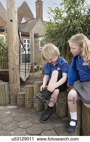 School girl watching boy tying shoelace on log fence View Large Photo Image Stock Image - School girl watching boy tying shoelace on log fence. Fotosearch