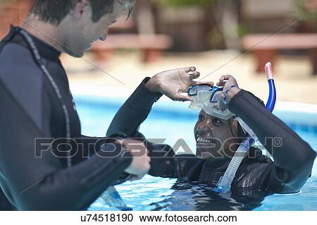 Stock Image - Scuba diving instructor with female pupil in swimming pool. Fotosearch