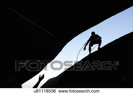 Silhouette of young male climbers reaching out for each other on rock View Large Photo Image Stock Photograph - Silhouette of young male climbers reaching out for each other on rock. Fotosearch