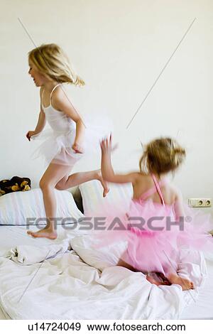 Sisters dressed as ballet dancers running on bed View Large Photo Image Stock Photo - Sisters dressed as ballet dancers running on bed. Fotosearch