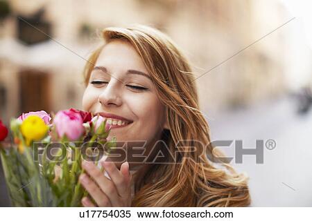 Smiling young woman smelling a bunch of flowers View Large Photo Image Stock Photography - Smiling young woman smelling a bunch of flowers. Fotosearch