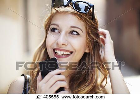 Sophisticated young woman with smartphone looking up View Large Photo Image Stock Photography - Sophisticated young woman with smartphone looking up. Fotosearch
