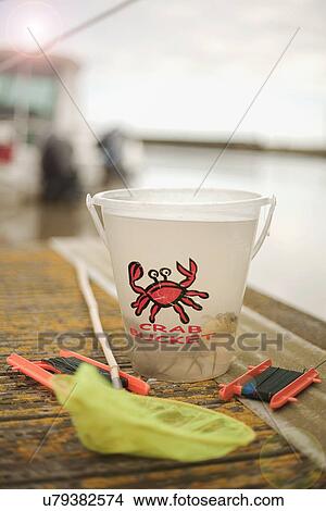 Picture - Still life of children's fishing net and crab bucket on a pier. Fotosearch
