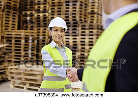 Picture - Supervisor and trainee shaking hands in distribution warehouse. Fotosearch