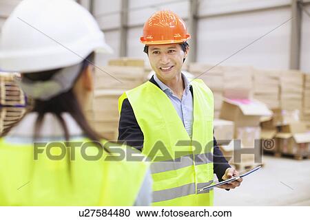 Stock Image - Supervisor shaking hands with trainee in distribution warehouse. Fotosearch