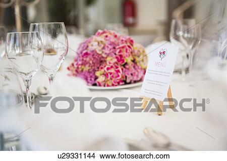 Table With Wine Glasses Menu And Flower Arrangement At Wedding