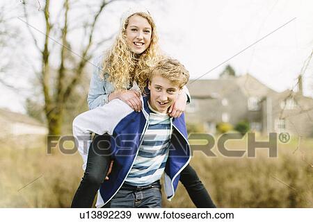 Stock Photo - Teenage boy giving girlfriend piggyback. Fotosearch