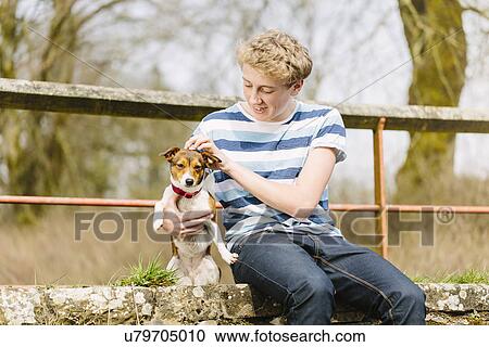 Teenage boy sitting on footbridge with his jack russell dog View Large Photo Image Stock Image - Teenage boy sitting on footbridge with his jack russell dog. Fotosearch