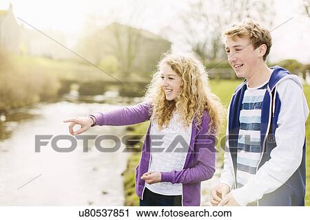 Stock Image - Teenage brother and sister on rural riverbank. Fotosearch