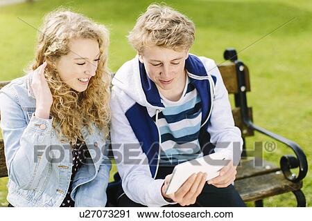 Teenage siblings looking at digital tablet on bench View Large Photo Image Stock Image - Teenage siblings looking at digital tablet on bench. Fotosearch