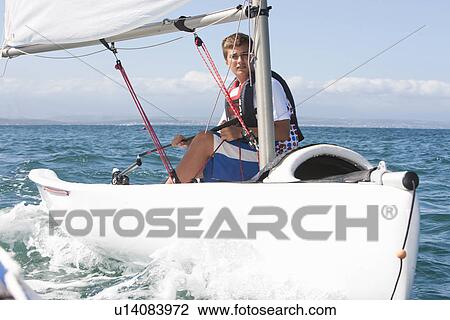 Stock Image - Teenager sailing boat. Fotosearch