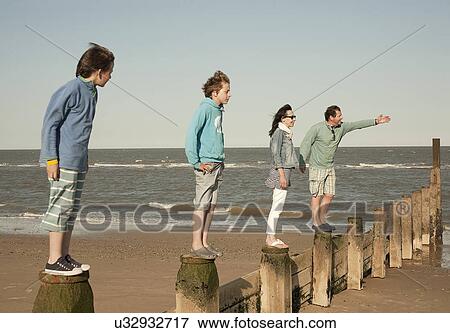 Two brothers and parents balancing on beach posts, Southwold, Sussex, UK View Large Photo Image Stock Photo - Two brothers and parents balancing on beach posts, Southwold, Sussex, UK. Fotosearch
