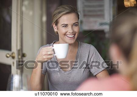 Two young adult female friends chatting in cafe View Large Photo Image Stock Image - Two young adult female friends chatting in cafe. Fotosearch