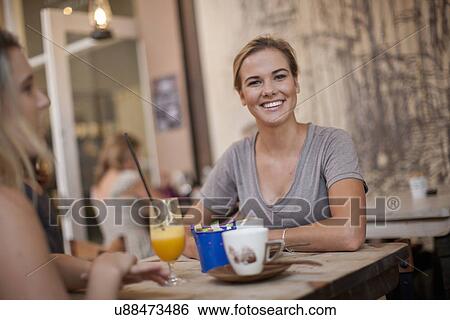 Stock Photograph - Two young adult female friends enjoying a chat in cafe. Fotosearch